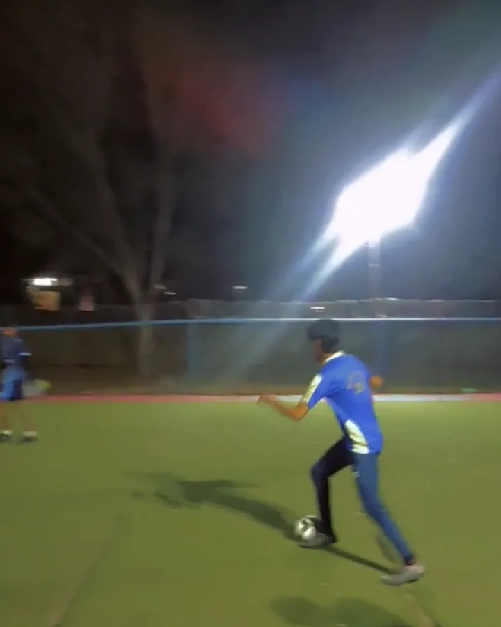 Umer playing football on a floodlit pitch at night